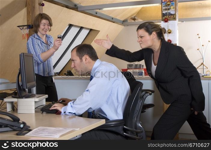 Businesswoman taking a picture of her colleague making fun of a businessman behind his back