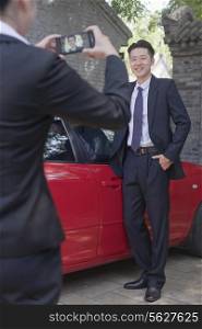 Businesswoman Taking Businessman&rsquo;s Picture Next to His Car