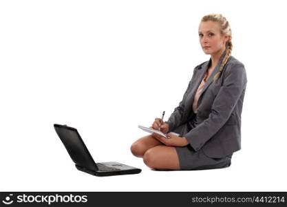 Businesswoman taking notes in front of her laptop