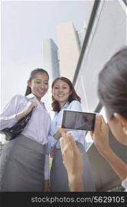 Businesswoman taking photo of her co-workers with her cell phone