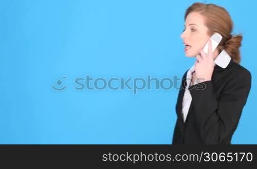 Businesswoman Talking Into Mobile Phone, upper body isolated on blue with copyspace.