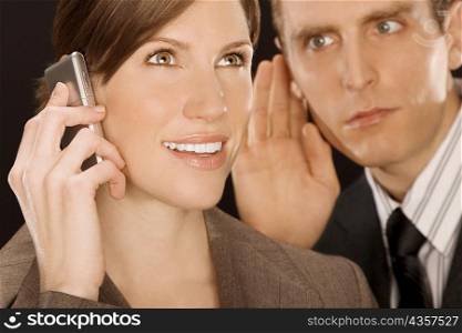 Businesswoman talking on a mobile phone and a businessman listening to her