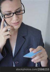 Businesswoman talking on a mobile phone and holding a credit card