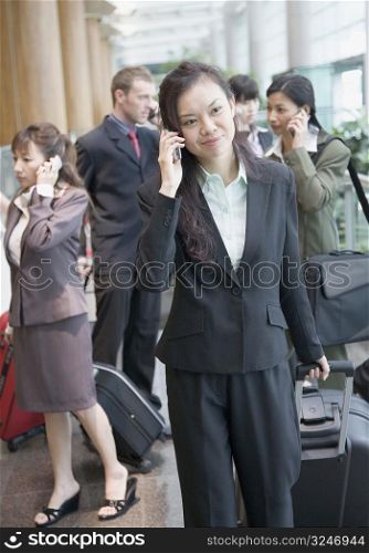 Businesswoman talking on a mobile phone and leaving an airport