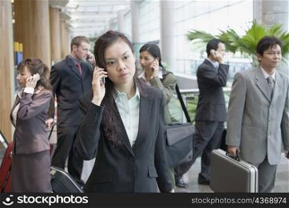 Businesswoman talking on a mobile phone and leaving an airport