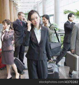 Businesswoman talking on a mobile phone and leaving an airport