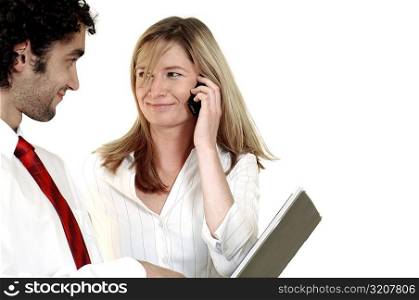 Businesswoman talking on a mobile phone looking at a businessman
