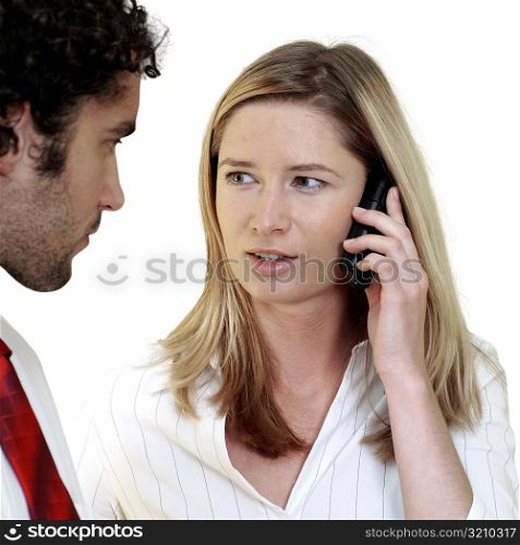 Businesswoman talking on a mobile phone looking at a businessman