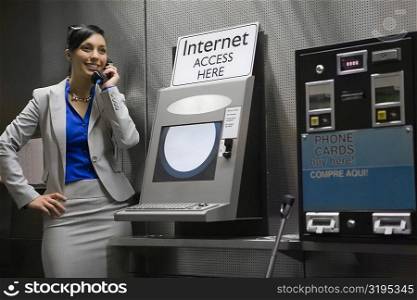 Businesswoman talking on a pay phone at an airport and smiling