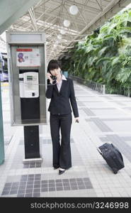 Businesswoman talking on a public phone at an airport