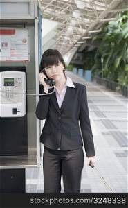 Businesswoman talking on a public phone at an airport