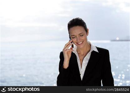 Businesswoman talking on her mobile phone on the waterfront