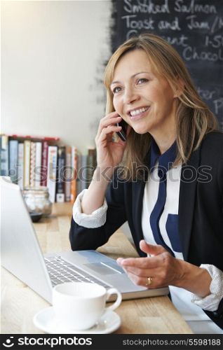 Businesswoman Talking On Mobile Phone In Cafe
