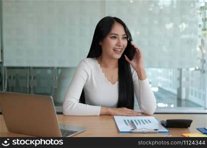 businesswoman talking on smartphone at office. young asian freelance woman female entrepreneur using mobile phone. business concept