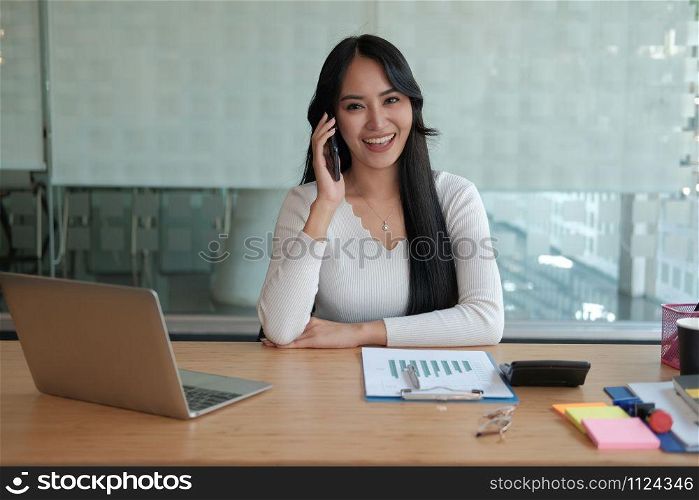 businesswoman talking on smartphone at office. young asian freelance woman female entrepreneur using mobile phone. business concept