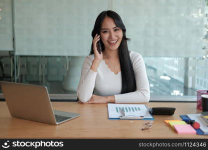 businesswoman talking on smartphone at office. young asian freelance woman female entrepreneur using mobile phone. business concept