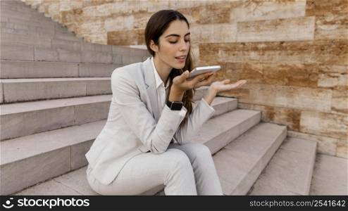 businesswoman talking phone while sitting outdoors stairs