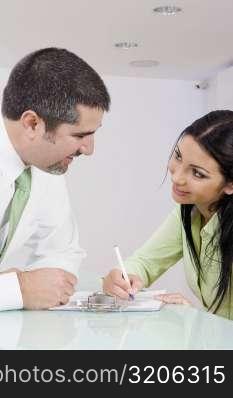 Businesswoman talking to a businessman while writing