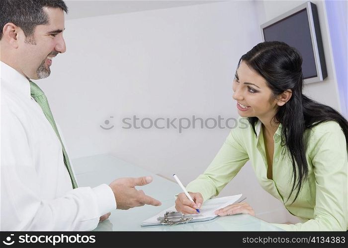 Businesswoman talking to a businessman while writing