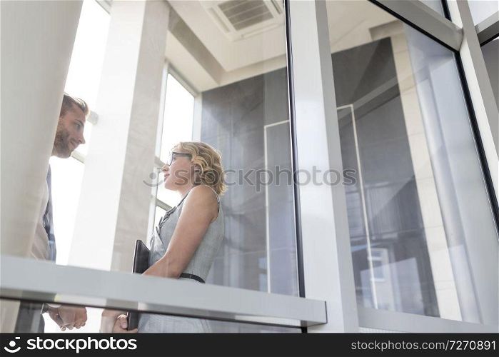 Businesswoman talking with young businessman seen through glass at new office