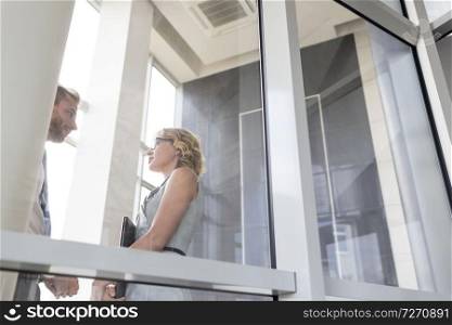Businesswoman talking with young businessman seen through glass at new office