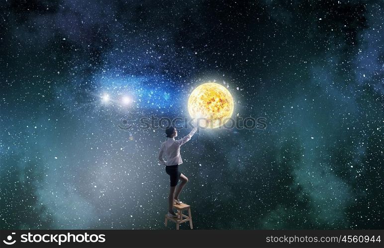 Businesswoman touch planet in sky. Businesswoman standing on chair and reaching space planets