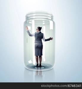 Businesswoman trapped inside a transparent glass jar