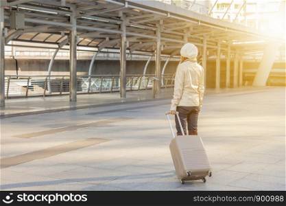Businesswoman traveler with luggage at city background