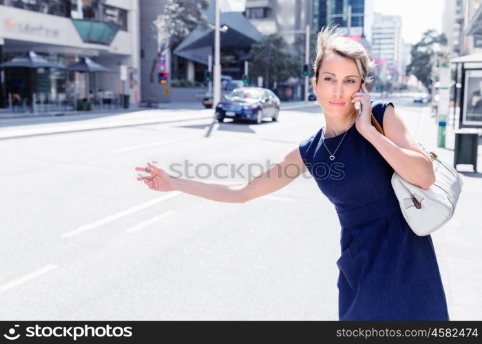 Businesswoman trying to catch a taxi in business cuty district. Waving for a taxi in city