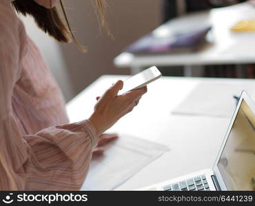 Businesswoman typing on phone while browsing internet at work in office