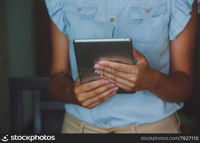 Businesswoman uses digital tablet. Businesswoman uses digital tablet. The tablet has a gray case and a glass screen. The woman in blue shirt.