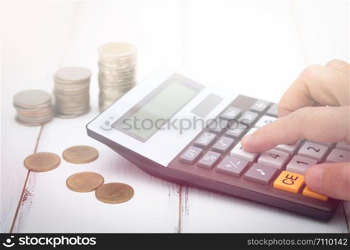 Businesswoman using a calculator have many coin on desk, Choose focus point.