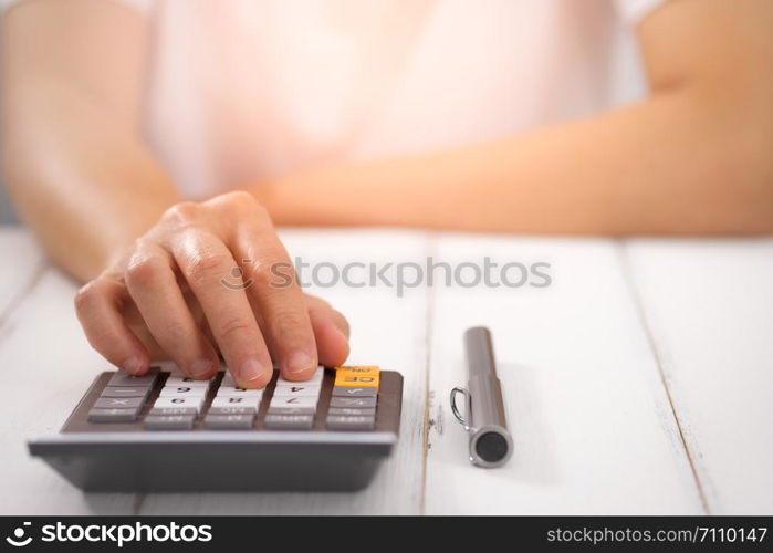 Businesswoman using a calculator on desk, Choose focus point. In over light.