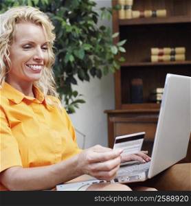 Businesswoman using a laptop and holding a credit card
