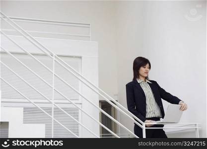 Businesswoman using a laptop on a staircase