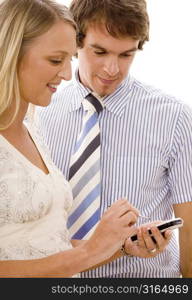 Businesswoman using a personal data assistant with a businessman standing beside her