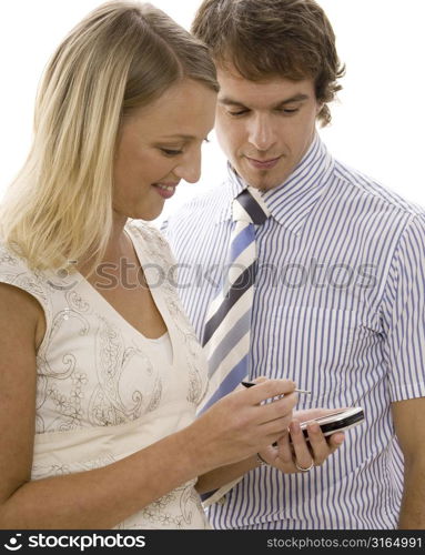 Businesswoman using a personal data assistant with a businessman standing beside her