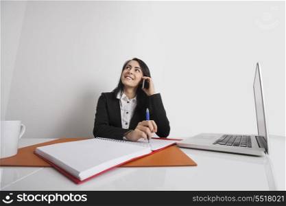 Businesswoman using cell phone at office desk