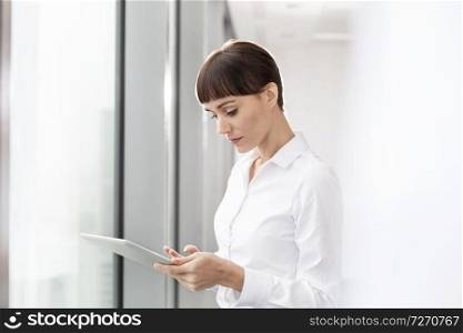 Businesswoman using digital tablet while standing in boardroom at office