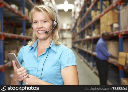 Businesswoman Using Headset In Distribution Warehouse