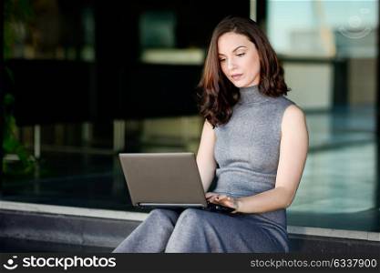 Businesswoman using her laptop computer sitting in a modern office building