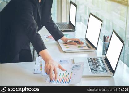 businesswoman using laptop at office desk and many document data graph in morning light, business concept.