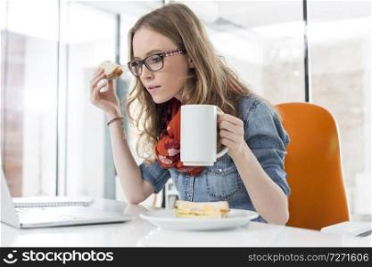Businesswoman using laptop computer while having breakfast in office