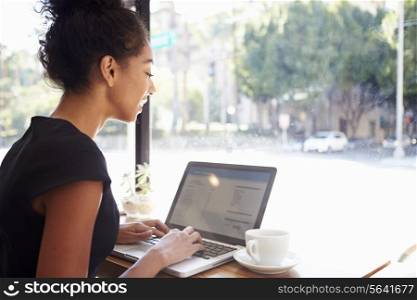 Businesswoman Using Laptop In Coffee Shop