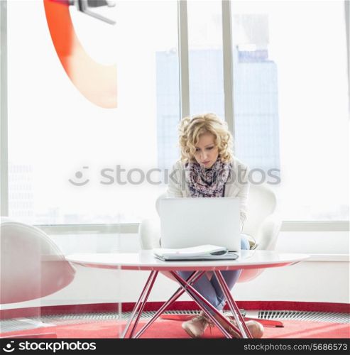 Businesswoman using laptop in creative office