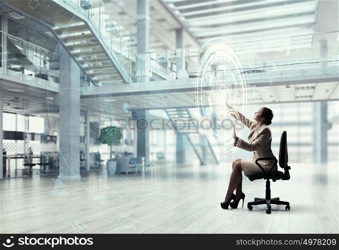 Businesswoman using media panel. Businesswoman sitting in chair and using virtual interface