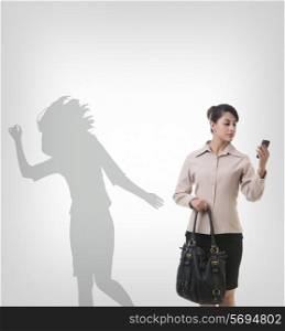 Businesswoman using mobile phone against shadow dancing over gray background
