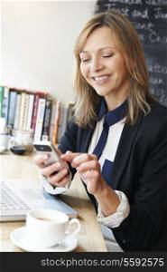 Businesswoman using mobile phone in cafe