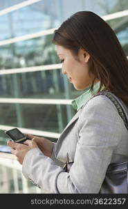 Businesswoman using mobile phone outside office building