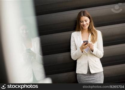 Businesswoman using mobile phone standing near office building